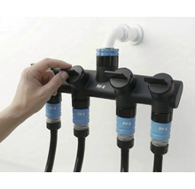 Trädgårdsslangfördelare med fyra anslutningar och en hand som manövrerar en av kranarna