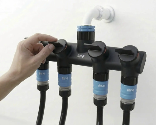 Trädgårdsslangfördelare med fyra anslutningar och en hand som manövrerar en av kranarna