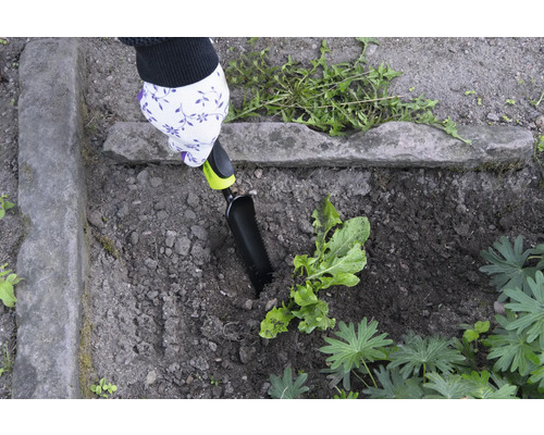 Trädgårdsarbete med en handspatel i en rabatt