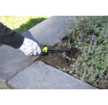 En person använder en trädgårdskultivator för att luckra upp jorden i en upphöjd trädgård.