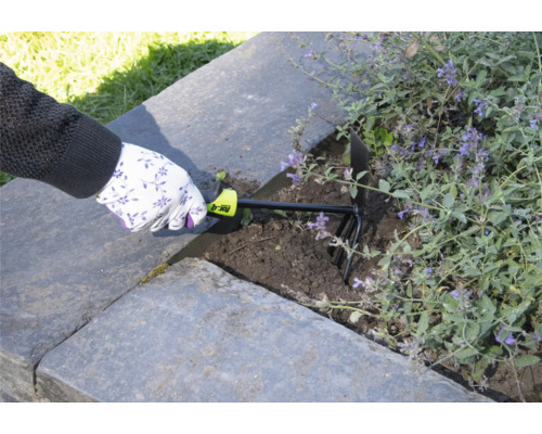 En person använder en trädgårdskultivator för att luckra upp jorden i en upphöjd trädgård.