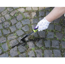 En person tar bort ogräs med en fogskrapa från en stensatt gångväg.