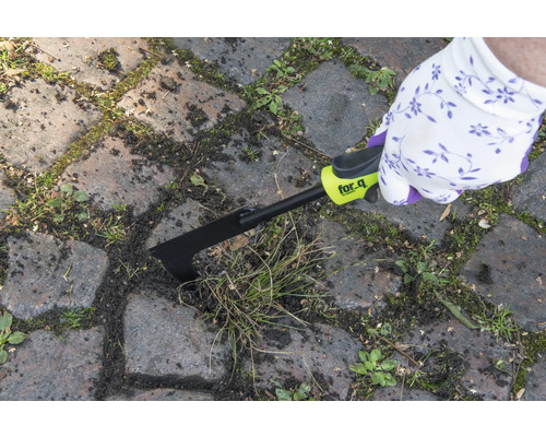 Person tar bort ogräs mellan gatstenar med en fogskrapa från for_q.