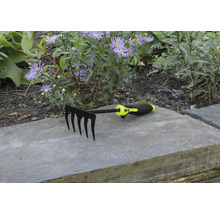 Trädgårdsräfsa med fem pinnar framför blomsterrabatt