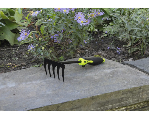 Trädgårdsräfsa med fem pinnar framför blomsterrabatt