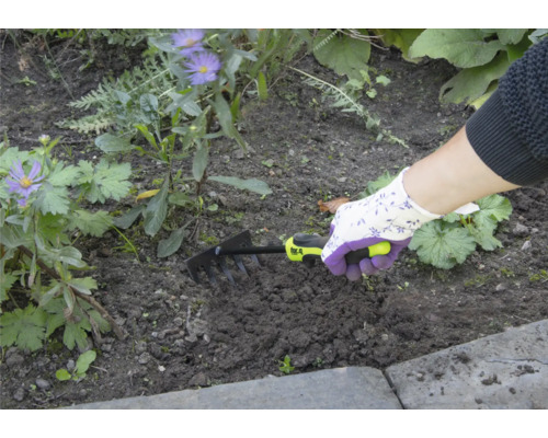 Person använder en liten kratta för trädgårdsarbete