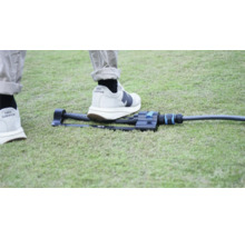 Trädgårdsspridare på gräsmatta med fot för storleksjämförelse.