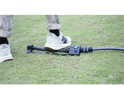 Trädgårdsspridare på gräsmatta med fot för storleksjämförelse.