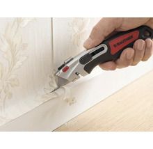 Hand med Rautner brytbladskniv som precist skär bort tapet med blommönster längs en golvlist.