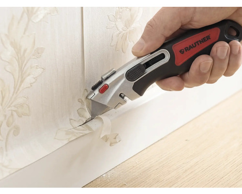 Hand med Rautner brytbladskniv som precist skär bort tapet med blommönster längs en golvlist.