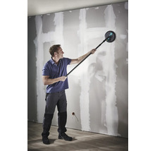 En man slipar en gipsvägg med en långhalsslip med teleskopiskt skaft.