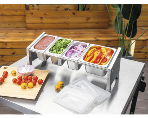 Tenneker Prep Station i rostfritt stål med fyra Gastronorm-behållare på ett metallbord, fylld med såser och skivade grönsaker för grillning.