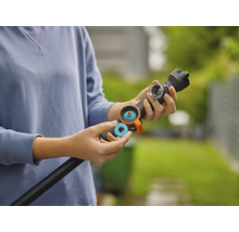 En person sätter in en blå tätningsring eller ett filter i en svart bevattningsstav för trädgården.