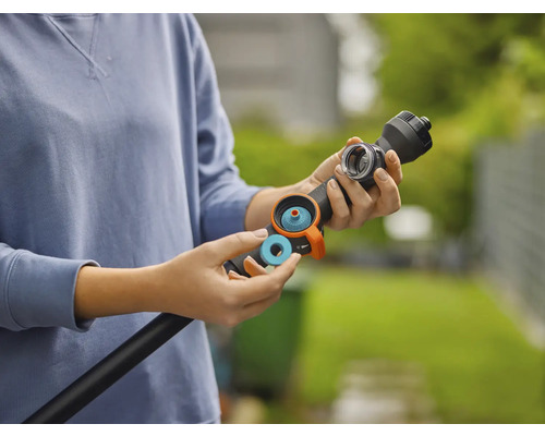 En person sätter in en blå tätningsring eller ett filter i en svart bevattningsstav för trädgården.