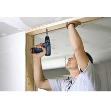 Person som använder en Bosch sladdlös borrskruvdragare för att arbeta på en träram under en renovering.