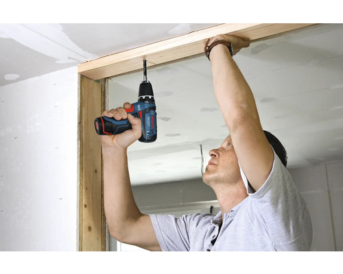 Person som använder en Bosch sladdlös borrskruvdragare för att arbeta på en träram under en renovering.