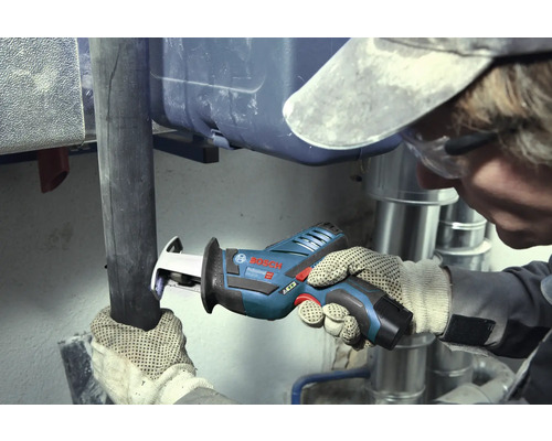 Hantverkare skär ett mörkt rör med en Bosch Professional sladdlös tigersåg i ett arbetsområde med silverfärgade metallrör.