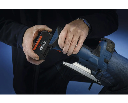 En person sätter i ett batteri från Bosch Professional 18 volt-systemet i en sticksåg.