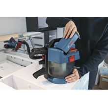 En person sätter i ett 18 volts batteri i en Bosch Professional batteridriven dammsugare GAS 18 Volt-1 i en verkstad.