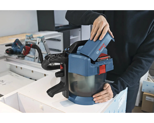 En person sätter i ett 18 volts batteri i en Bosch Professional batteridriven dammsugare GAS 18 Volt-1 i en verkstad.