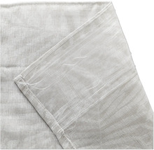 Detaljbild av ett gardintyg med påsytt universalband för gardinkrokar.