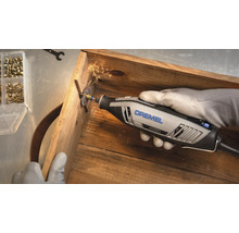 Dremel 4250 multiverktyg kapar en skruv i en trälåda med gnistor.