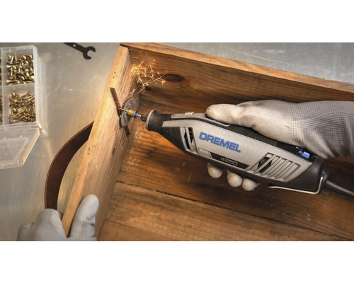 Dremel 4250 multiverktyg kapar en skruv i en trälåda med gnistor.
