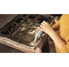 En person använder ett Dremel 4250 multiverktyg för att bearbeta en träram med metallgaller.