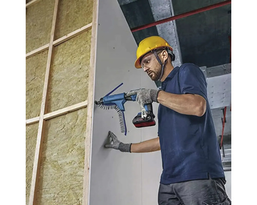 Yrkesman monterar gipsskivor på en isolerad trävägg med en batteridriven gipsskruvdragare med magasin.