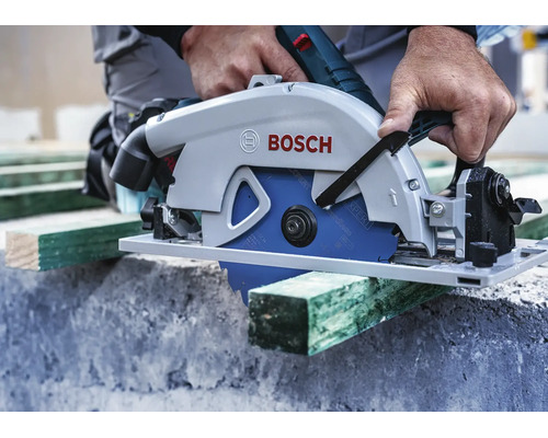 Hantverkare sågar en träplanka med en Bosch handhållen cirkelsåg på en byggarbetsplats.