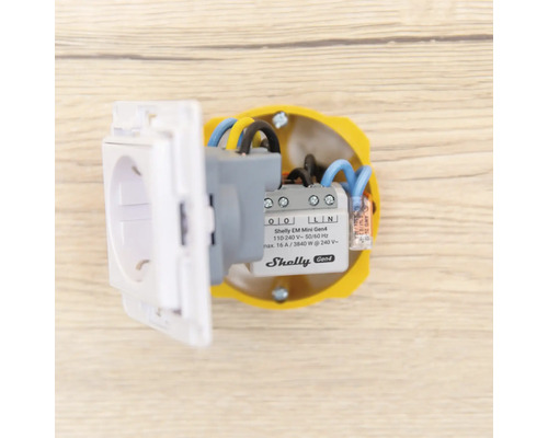 Shelly EM Mini Generation 4 energimätare installerad i en infälld dosa bakom ett eluttag.