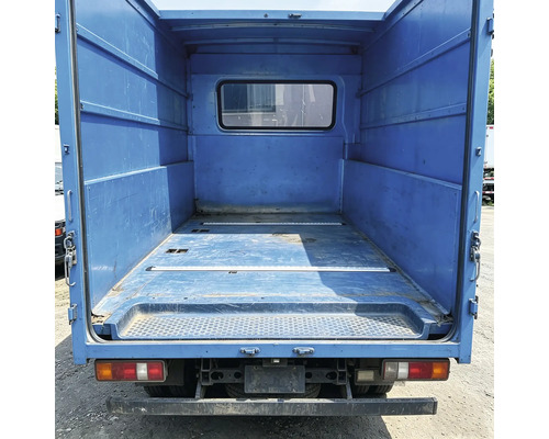 Tomt lastutrymme på en transportbil med metallväggar och ett fönster i mellanväggen.