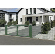 Dubbel grind och staket av grönt dubbelpanelstängsel framför ett modernt hus med vit fasad och grusträdgård.