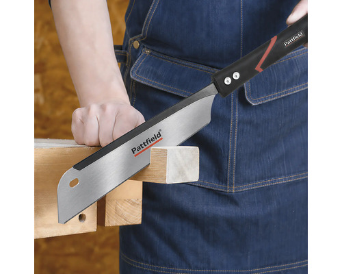 Pattfield handsåg som sågar i en träregel som hålls av en person i ett förkläde av denim.