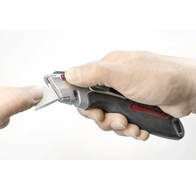 Hand som håller en Rautner trapetskniv med ergonomiskt grepp under ett bladbyte.