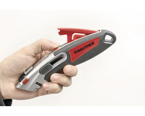 Hand som håller en Rautner säkerhetskniv med infällbart blad och ergonomiskt handtag.