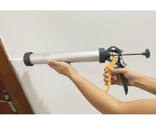 En person använder en Precit fogpistol för fogpåsar för att täta en fog mellan väggen och dörrkarmen.