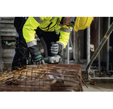 Hantverkare som använder en sladdlös vinkelslip från Metabo för att skära armeringsjärn på en byggarbetsplats, gnistregn, skyddsutrustning.