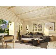 Ljus interiör i en friggebod av trä med soffa, soffbord och stora fönster.