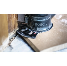Bosch multiverktyg med instickssågblad sågar ett trägolv jämnt mot en vägg.