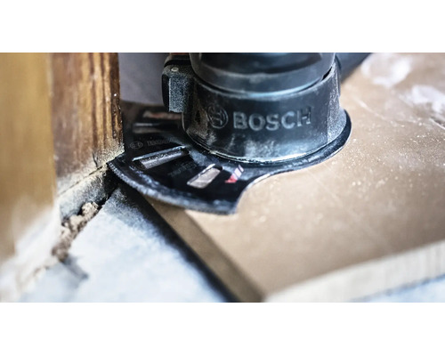 Bosch multiverktyg med instickssågblad sågar ett trägolv jämnt mot en vägg.