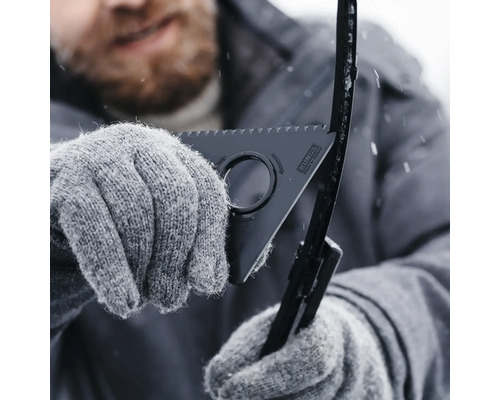 En person med handskar använder en torkarbladsrengörare för att avgrada och rengöra ett torkarblad under vintern.