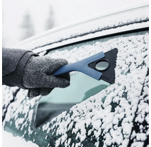 Isskrapa i handen på en person med handskar som tar bort snö och is från en bilruta