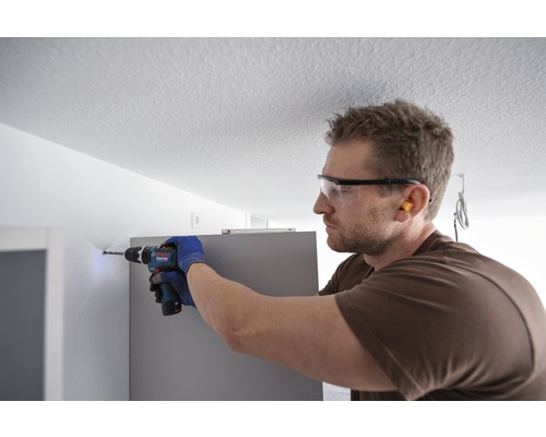 Hantverkare borrar ett hål i väggen med en borrmaskin.