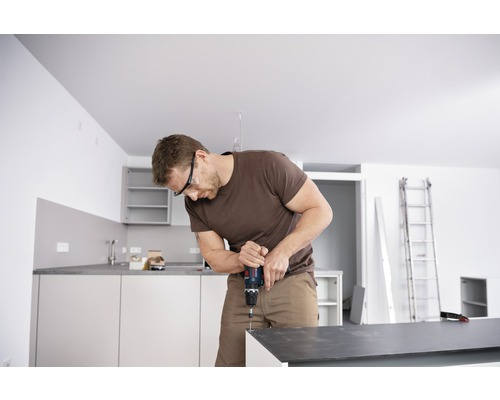 Man monterar kök med sladdlös skruvdragare och skyddsglasögon