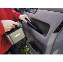 Person dammsuger bilens interiör med en sladdlös dammsugare av märket Worx