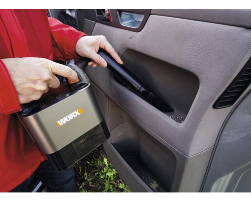 Person dammsuger bilens interiör med en sladdlös dammsugare av märket Worx