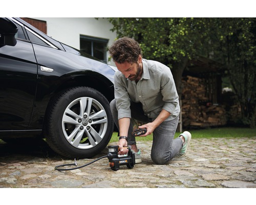 Man pumpar upp ett bildäck med en batteridriven kompressor