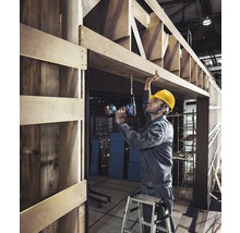 En hantverkare borrar ett hål i en träram med en sladdlös borr.