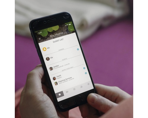 En person håller en smartphone med en app för hantering av gästlistor.